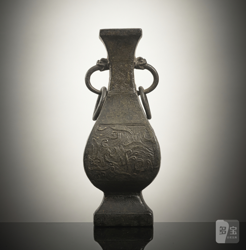 A four-sided bronze vase with wave decoration in relief and loose ring handles